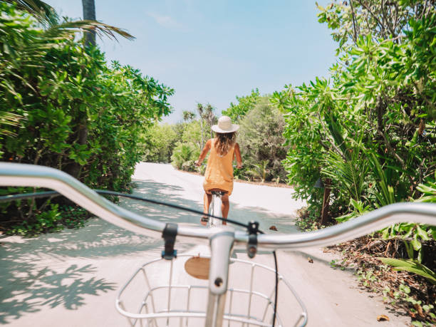 Pov point of view of couple cycling on tropical island Pov point of view of couple cycling on tropical island. Personal perspective of person cycling with girlfriend in front. Tropical luxury vacations  life in Maldives stock pictures, royalty-free photos & images