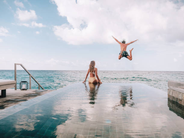 Couple enjoying luxury vacations Couple enjoying tropical vacations from the edge of an infinity pool in private over water villa. People travel luxury holidays honeymoon stock pictures, royalty-free photos & images