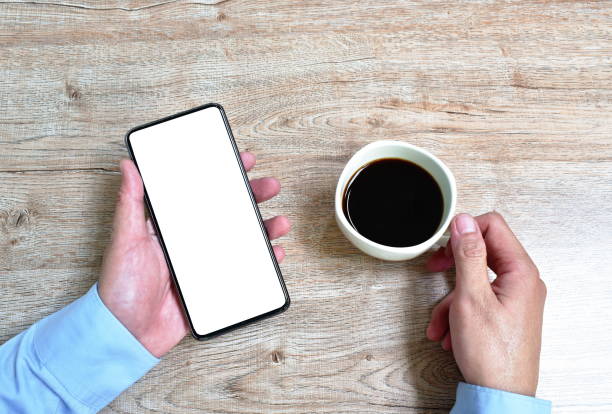 istock hand of businessman holding mobile phone with white screen while drinking black coffee cup 1264660517