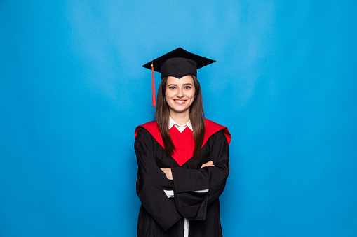 Young woman in graduation robe on blue background