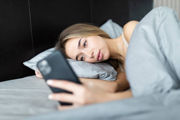 istock Young woman texting while lying on a bed at home 1264664014