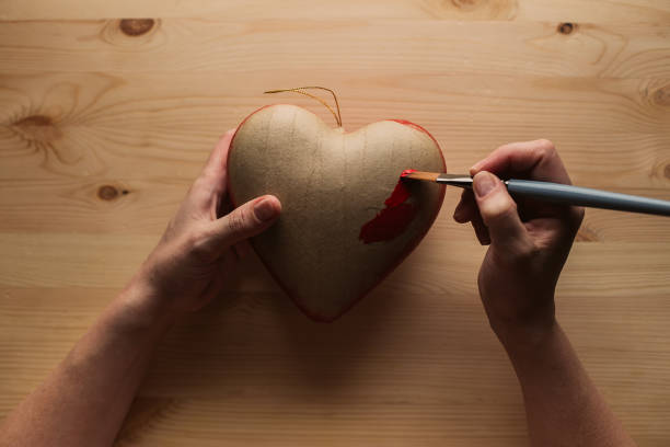 istock Hands paint the heart of papier mache 1264666120