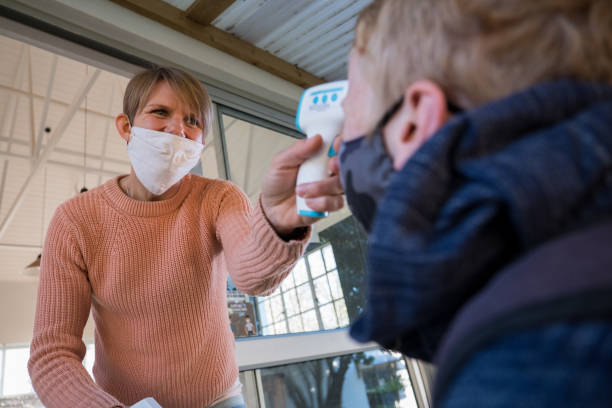 istock Teacher records a Childs temperature before he enters the classroom 1264666136