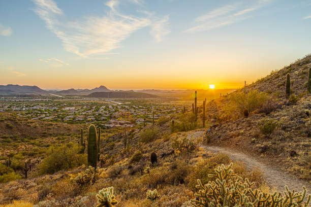 A desert trail on a mountain leading to a sunset over a valley in Phoenix stock photo