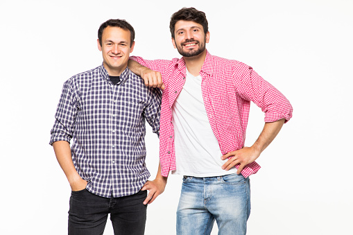 Two handsome men wearing casual t-shirt and jeans smiling and posing together on camera over white background