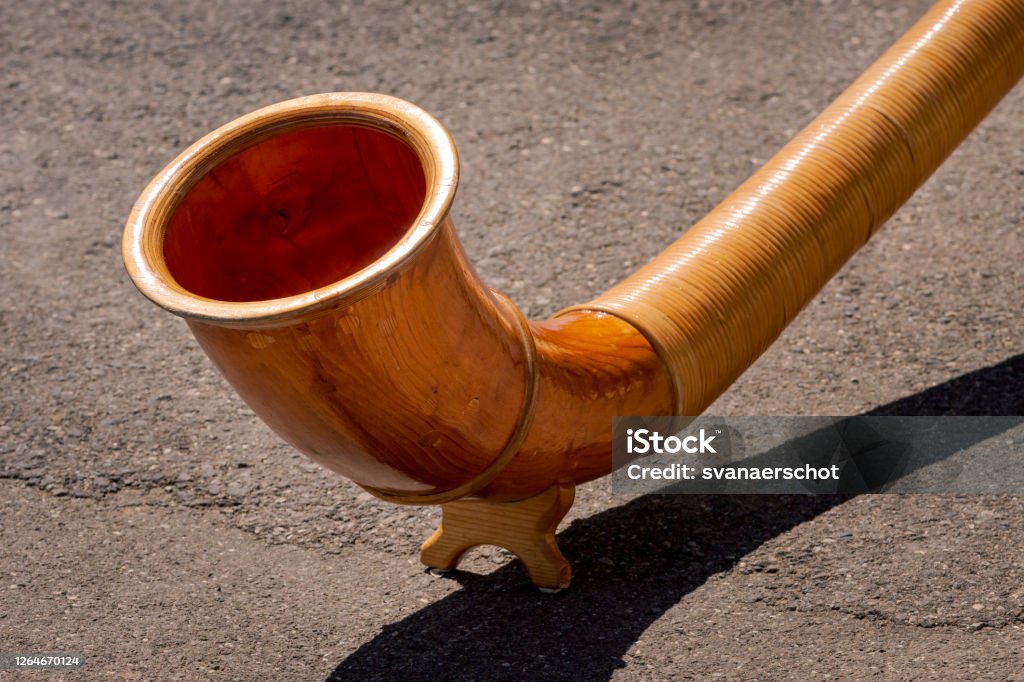 Close up of wooden Alphorn A close up view of the end of wooden Alphorn (Alpenhorn or Alpine horn) on a concrete background. Traditional instrument in Switzerland Alpenhorn Stock Photo