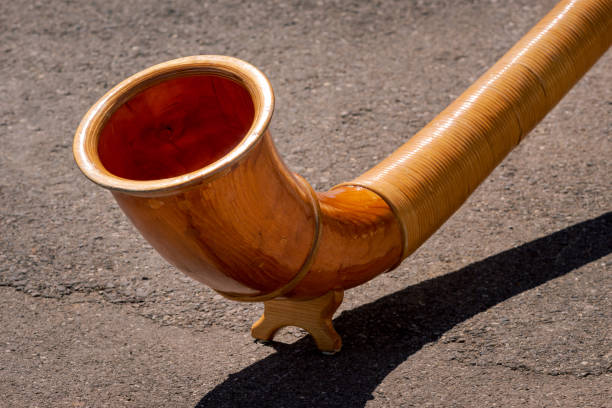 Close up of wooden Alphorn A close up view of the end of wooden Alphorn (Alpenhorn or Alpine horn) on a concrete background. Traditional instrument in Switzerland alpenhorn stock pictures, royalty-free photos & images