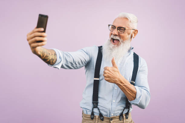 starszy mężczyzna za pomocą smartfona mobilnego i słuchanie muzyki - headphones music mobile phone tattoo zdjęcia i obrazy z banku zdjęć