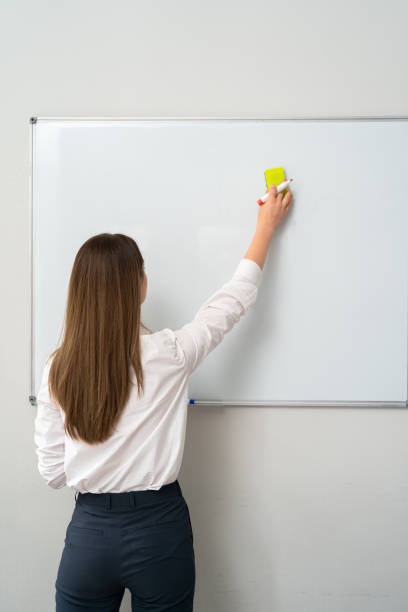 istock Young woman writing on a whiteboard in an office, 1264673519