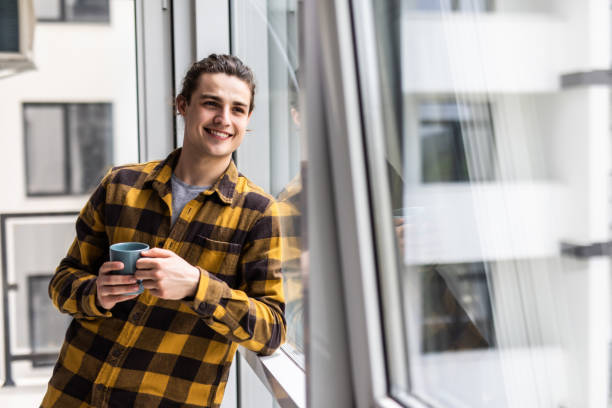 istock Eelaxed young man drink first morning coffee at modern home indoors at window 1264675548