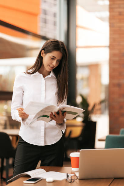 Businesswoman working while standing at table and smiling