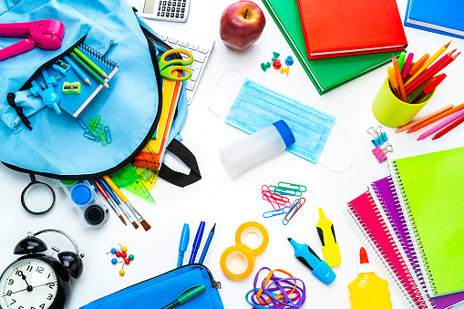 Back to school after COVID-19 pandemic outbreak: large group of multicolored school supplies, protective face mask and hand sanitizer bottle shot from above on white background. Kids safety at school after pandemic outbreak. High resolution 42Mp studio digital capture taken with SONY A7rII and Zeiss Batis 40mm F2.0 CF lens