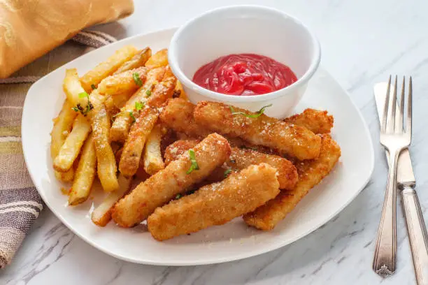 American fish sticks and french fries with ketchup on marble kitchen table