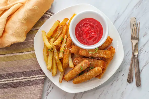 American fish sticks and french fries with ketchup on marble kitchen table