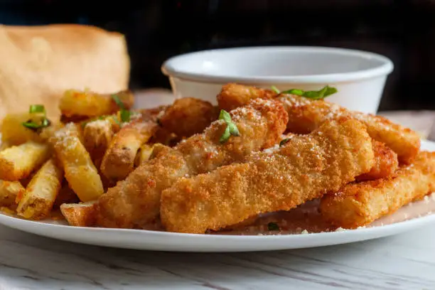 American fish sticks and french fries with ketchup on marble kitchen table