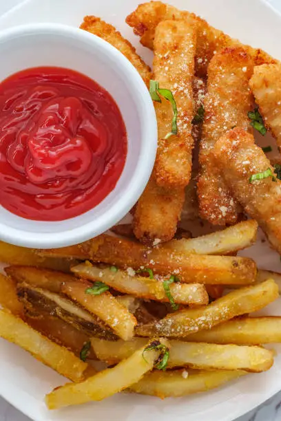 American fish sticks and french fries with ketchup on marble kitchen table