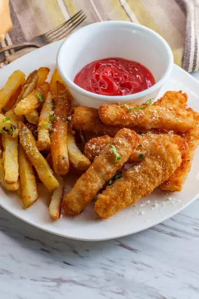 American fish sticks and french fries with ketchup on marble kitchen table