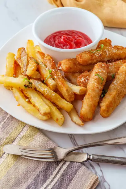 American fish sticks and french fries with ketchup on marble kitchen table