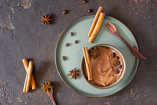 istock Coffee and chocolate pudding or mousse in a ceramic bowl with cinnamon and anise star, selective focus. Dark brown concrete background. 1264690404