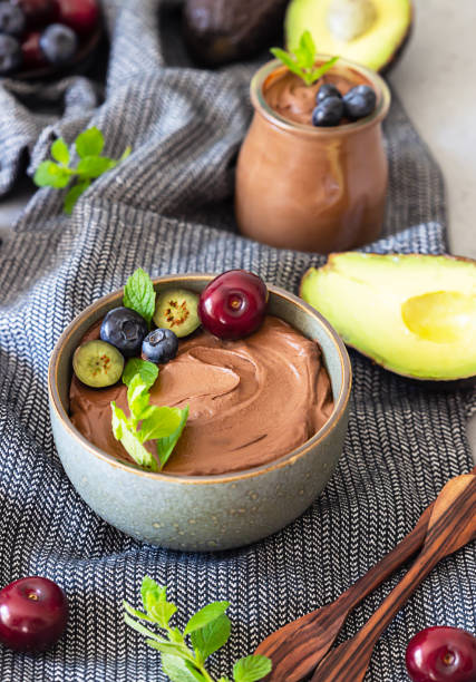 istock Raw avocado chocolate mousse topped with chocolate pieces, cherry, blueberry and mint, selective focus. Grey background. Healthy vegan chocolate dessert. 1264690491