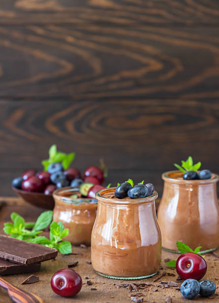 istock Portion jars with chocolate mousse or pudding decorated with sweet cherry, blueberry and mint and pieces of dark chocolate. Selective focus. Rustic style. Dark background. 1264690495