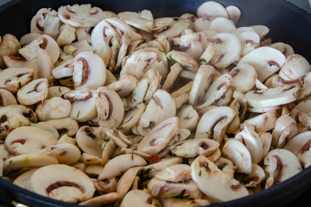 Champignon mushrooms are fried in a frying pan
