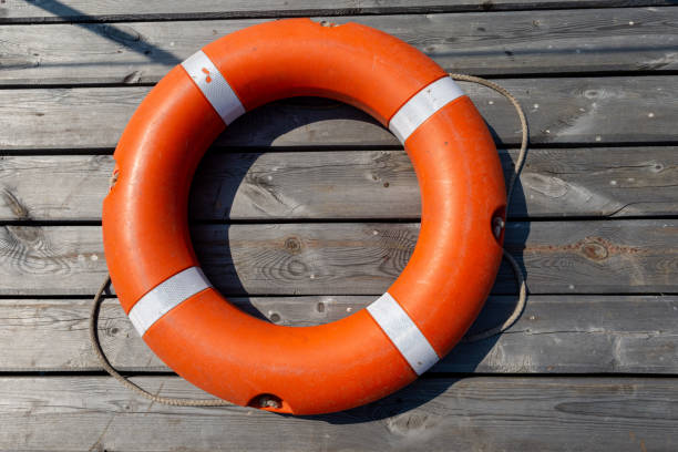 спасательный круг лежит на деревянном пирсе. концепция спасения утопления - ring buoy стоковые фото и изображения