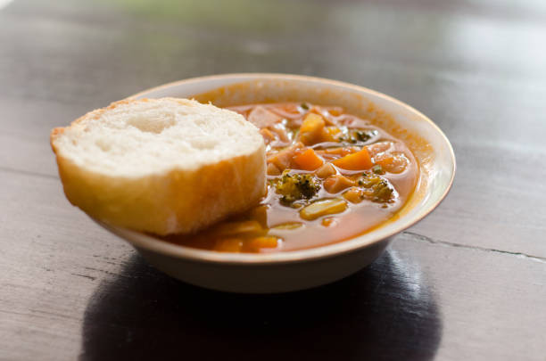 istock Tomato, red pepper, basil soup in white bowl with bread and spoon on a light gray background. 1264698570