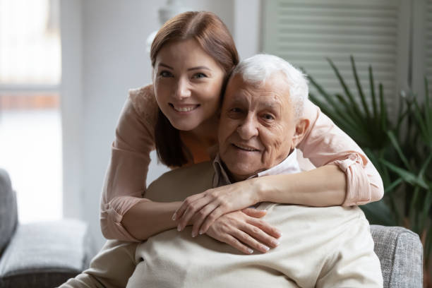 Head shot portrait smiling daughter hugging older father from back Head shot portrait smiling grownup daughter hugging older father from back, looking at camera, two generations concept, beautiful young woman embracing mature man, posing for photo together father daughter 80s stock pictures, royalty-free photos & images