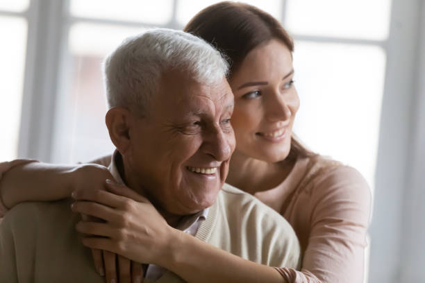 istock Close up smiling dreamy elderly man and young woman hugging 1264699596