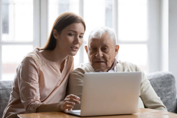 istock Caring grownup daughter teaching elderly father to use laptop 1264699605