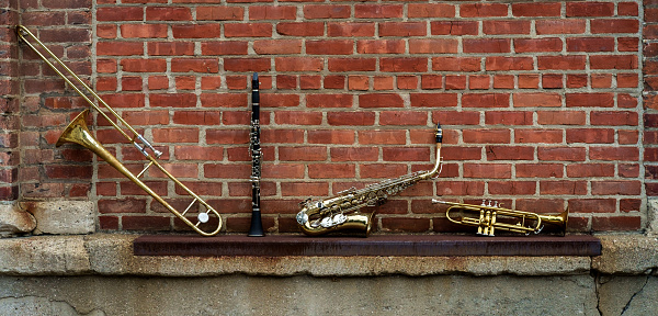 Musical instruments including trombone trumpet clarinet and saxophone on brick wall outside Jazz club