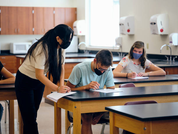 istock High School Teacher and Students In Classroom Wearing Protective Face Mask 1264703668