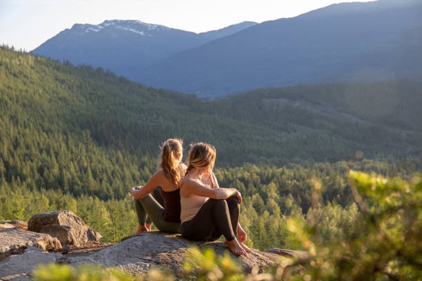 istock Young women relax on rock slabs, look off to view 1264705861