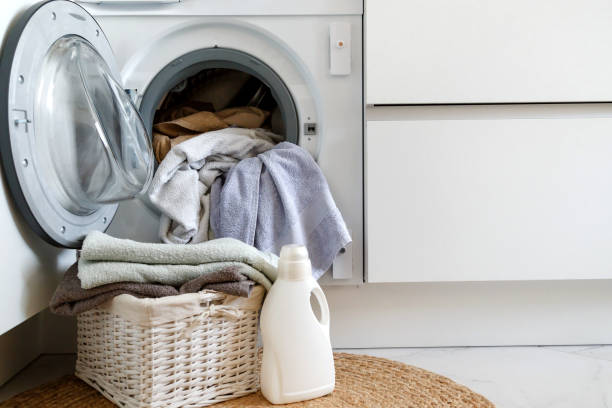 istock Loading a washing machine and washing clothes. A laundry basket and laundry gel in front of a household built-in washing machine in the kitchen. 1264705885