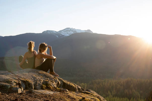 las mujeres jóvenes se relajan en losas de roca, miran a ver - growth tree spirituality tranquil scene fotografías e imágenes de stock