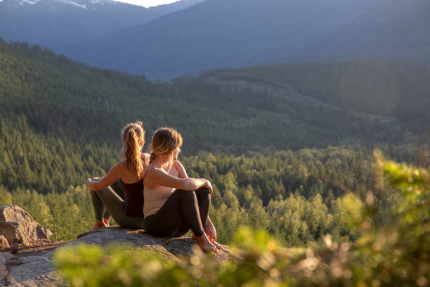 istock Young women relax on rock slabs, look off to view 1264706510