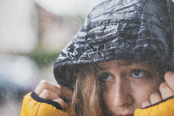 Close-up portrait of Asian, Indian beautiful, serene young woman wearing a winter cap, looking away and thinking deeply with a blank expression.