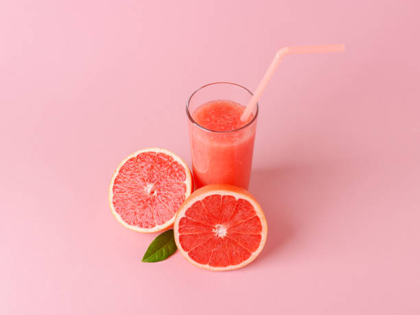 istock Glass of freshly squeezed grapefruit juice with pulp, drinking straw and two halves of grapefruit on a pink background. Vegetarian, raw food diet and healthy eating. 1264707694
