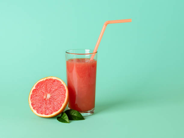 istock Glass of freshly squeezed grapefruit juice with pulp, drinking straw and half of grapefruit on a mint green background. Vegetarian, raw food diet and healthy eating. 1264707709