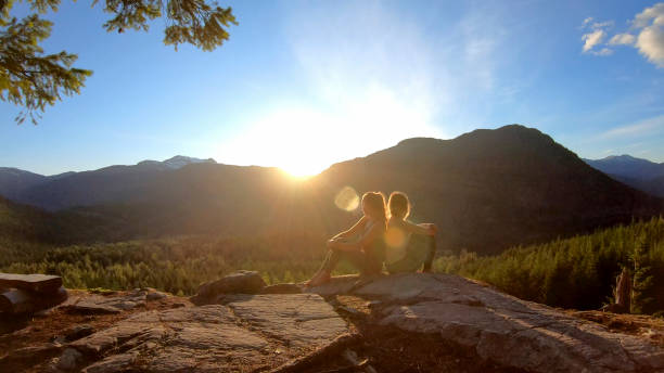 istock Young women relax on rock slabs, look off to view 1264708009