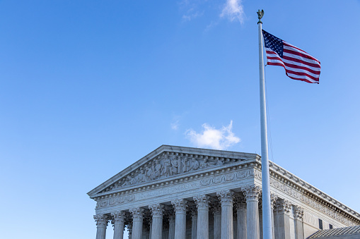 American flag waving out-front of the United States Supreme Court.