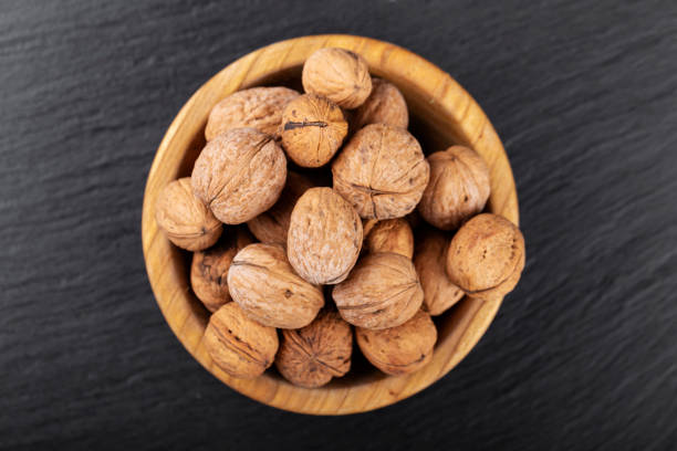 istock Walnut in wooden bowl on black background with copy space. 1264710794