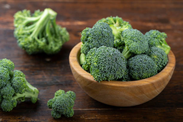 Fresh broccoli with in bowl on wooden table close up. Fresh broccoli with in bowl on wooden table close up. Fiber-rich food. broccoli crowns stock pictures, royalty-free photos & images