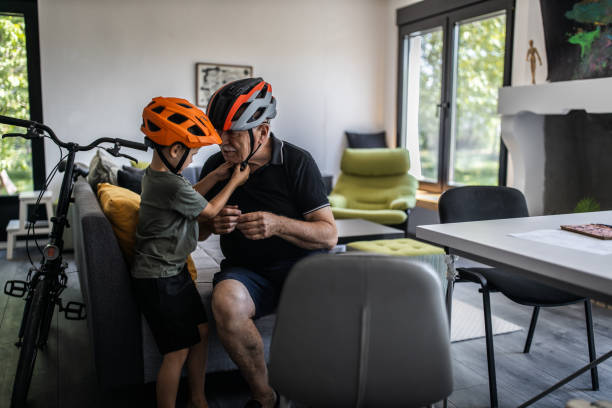 dziadek i wnuk siedzący w salonie i montując kaski rowerowe - cycling senior adult sports helmet men zdjęcia i obrazy z banku zdjęć