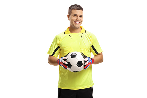 Soccer goalkeeper holding a ball and smiling isolated on white background