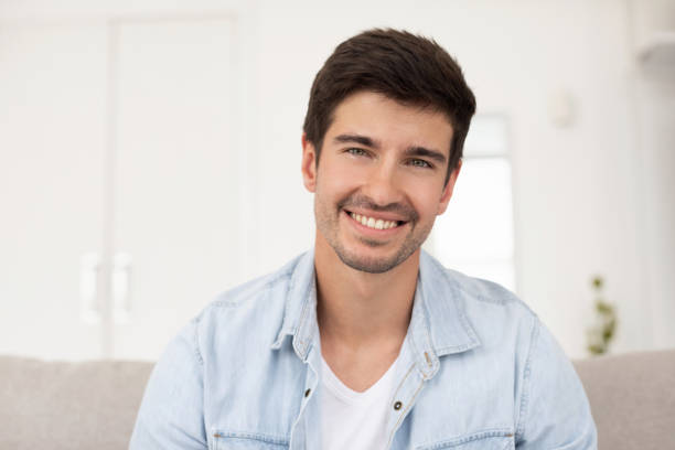 istock Happy guy smiling at camera sitting on sofa at home. 1264717941