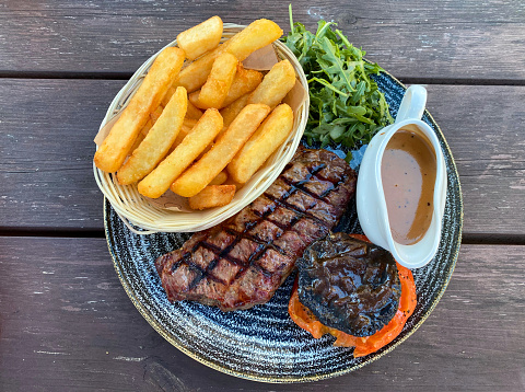 Grilled beef steak and fries with a pepper sauce