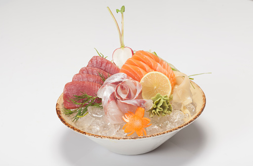 Tuna and salmon sashimi served with iced bowl on white background.