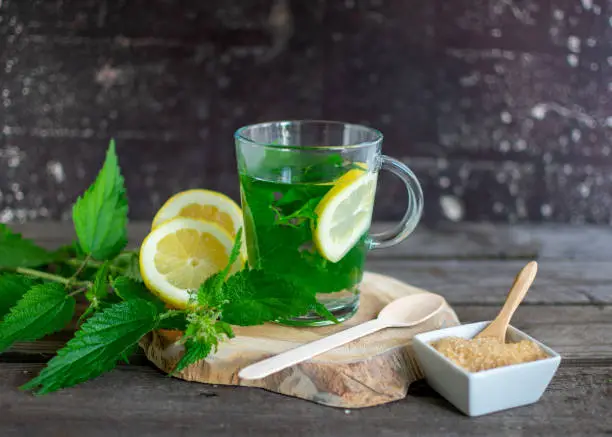 Fresh nettle tea with lemon on a wooden board with brown sugar